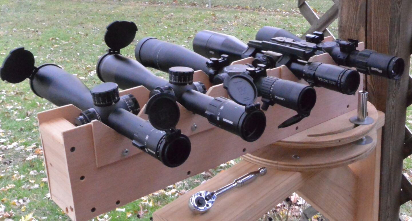 Testing optical performance in a V-block. From right to left: Minox ZP5 5-25x56, Minox 5-25x56 LR, Leupold Mark 5HD 5-25x56, Bushnell XRS3 6-36x56, Sig Tango6 5-30x56