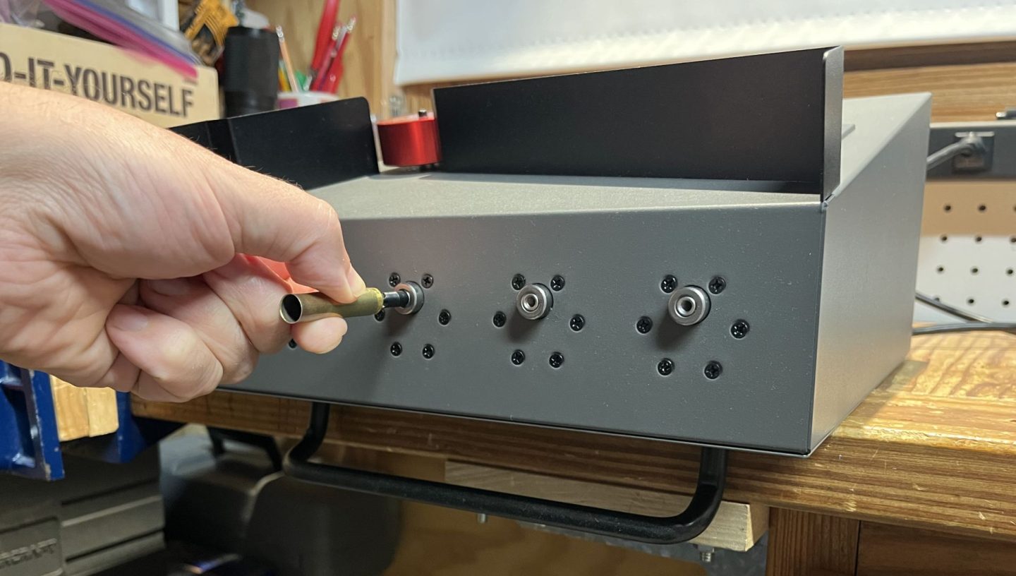 Removing a primer crimp from 350L brass using BurstFire’s primer crimp remover and 2-in-1 flame annealer laid on its back such that the carry handle makes for an excellent stop positioning the unit to drop shavings into a waste basket